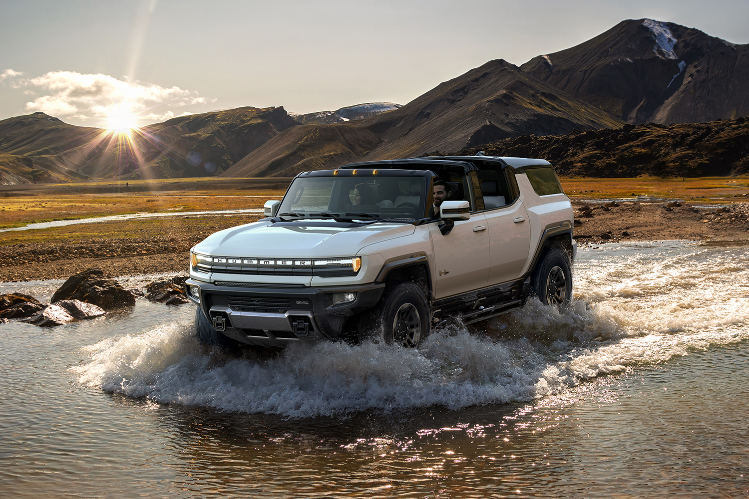 The 2024 GMC Hummer EV SUV fording a stream in the wilderness