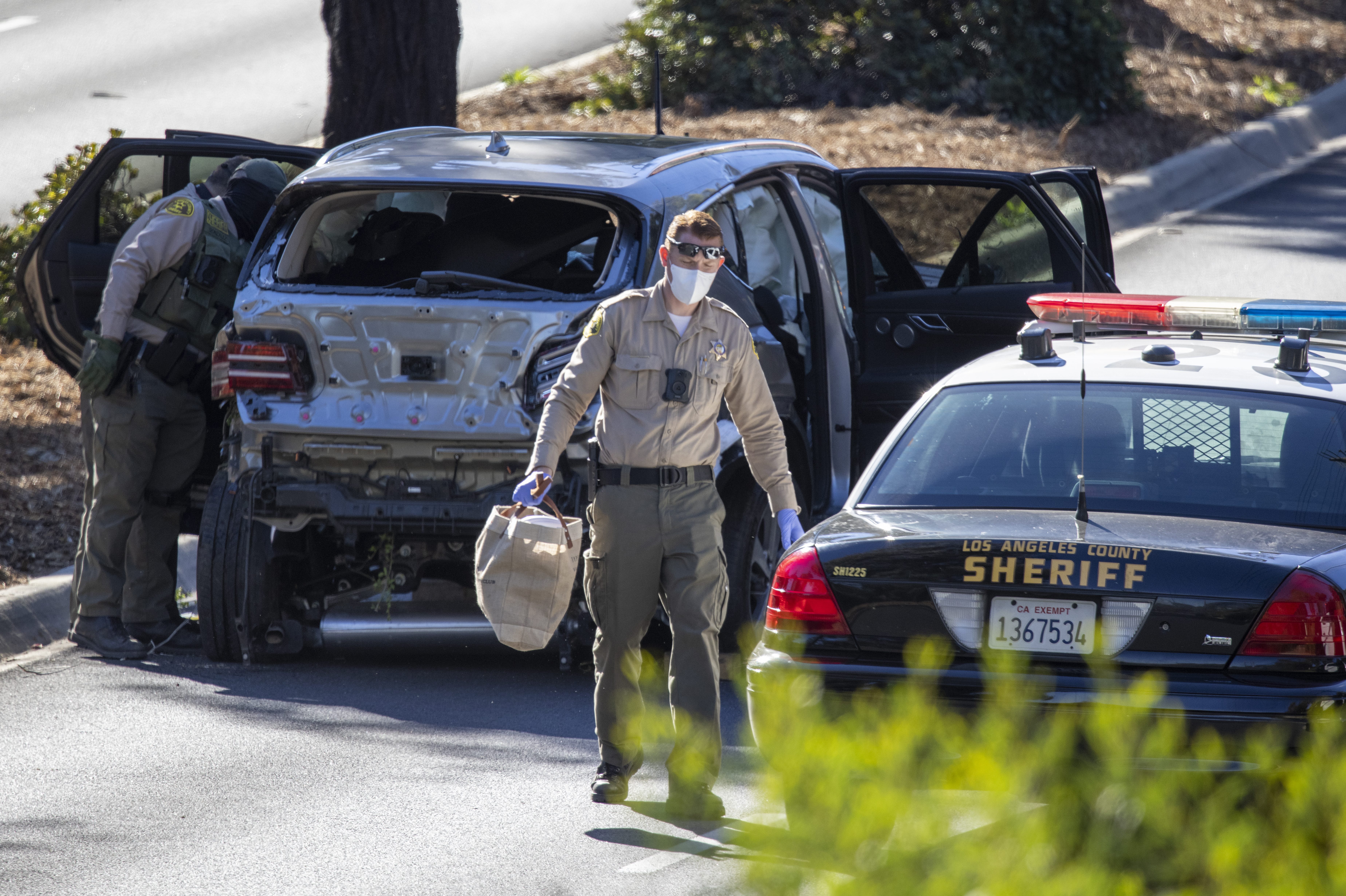 Los Angeles County Sherrif deputies with the vehicle that golf legend Tiger Woods crashed