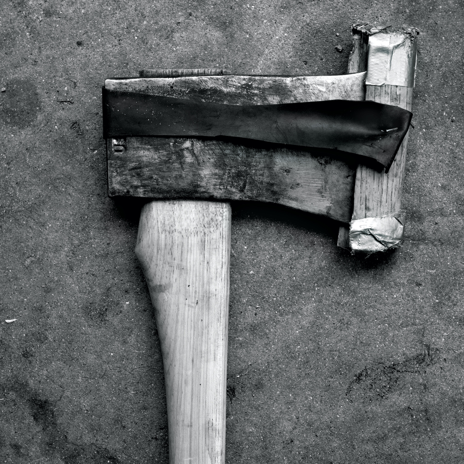 A black and white photo of a vintage axe on the ground