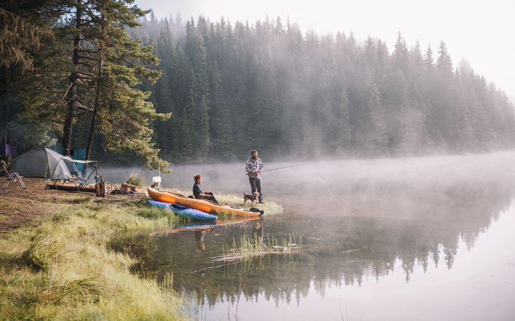 Camping Clothing with man fishing on the shore of a lake