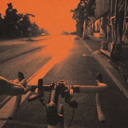 A hand holding the handlebars of a bicycle in a bike lane