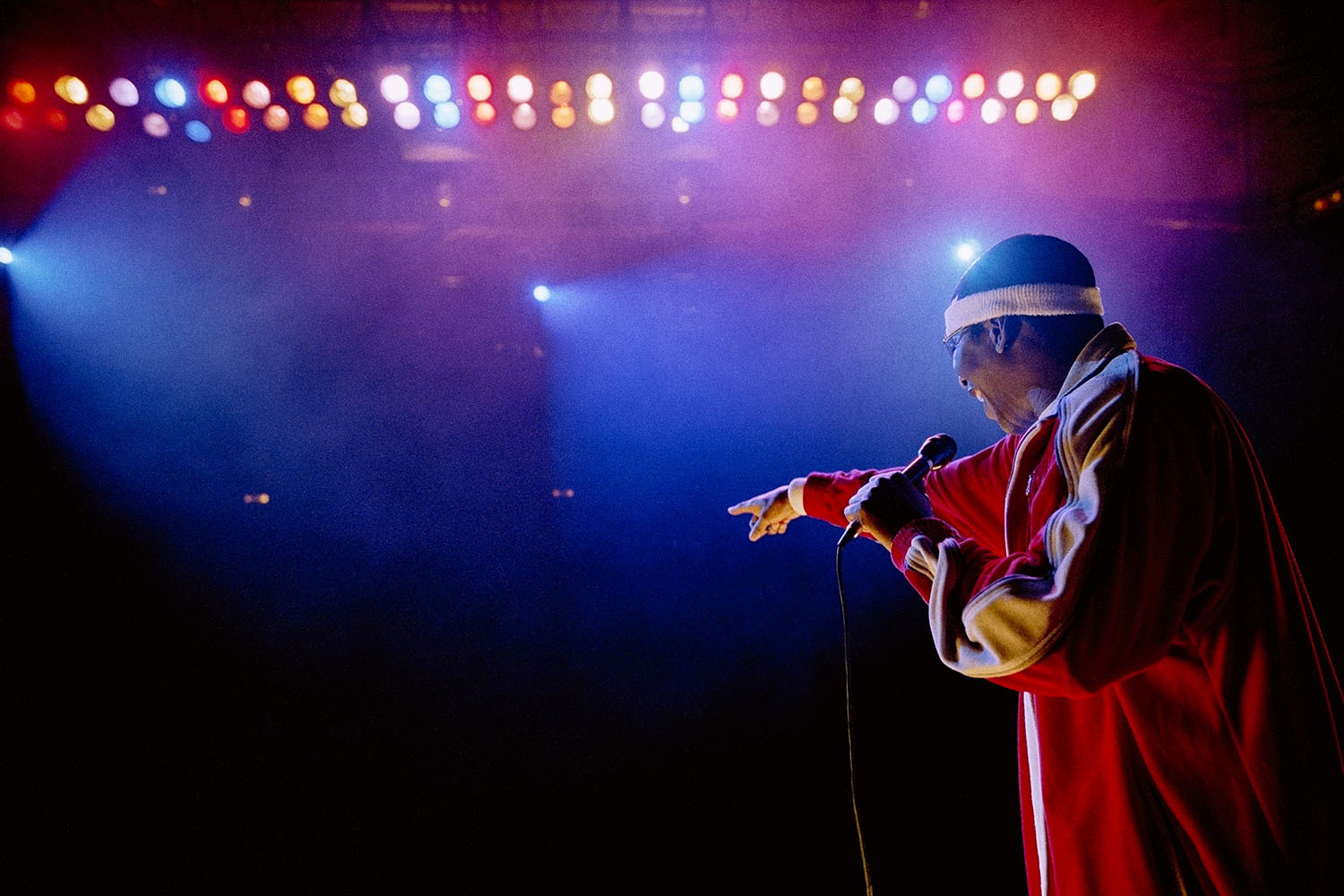 Rapper on stage under blue and purple stage lights, pointing out at audience