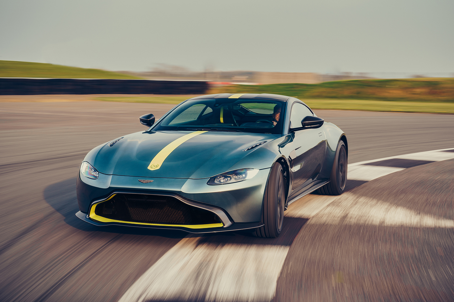 A green and yellow Aston Martin Vantage AMR speeding around a track