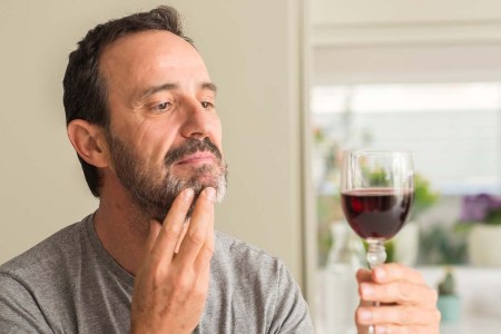 A middle age man drinking a glass of wine serious face thinking about question, very confused idea