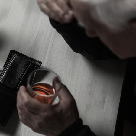 a man drinking whiskey with his wallet open