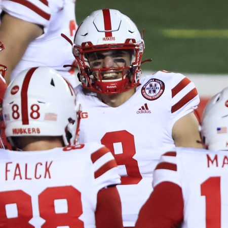 Nebraska Cornhuskers football players in red and white uniforms on the field. The school will soon help the players cash in on their name, image and likeness.