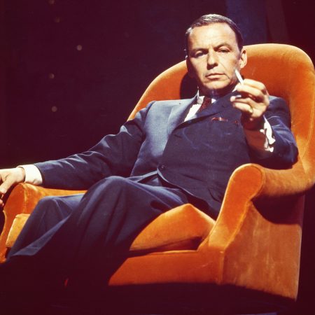 Frank Sinatra sitting in an orange chair in 1955