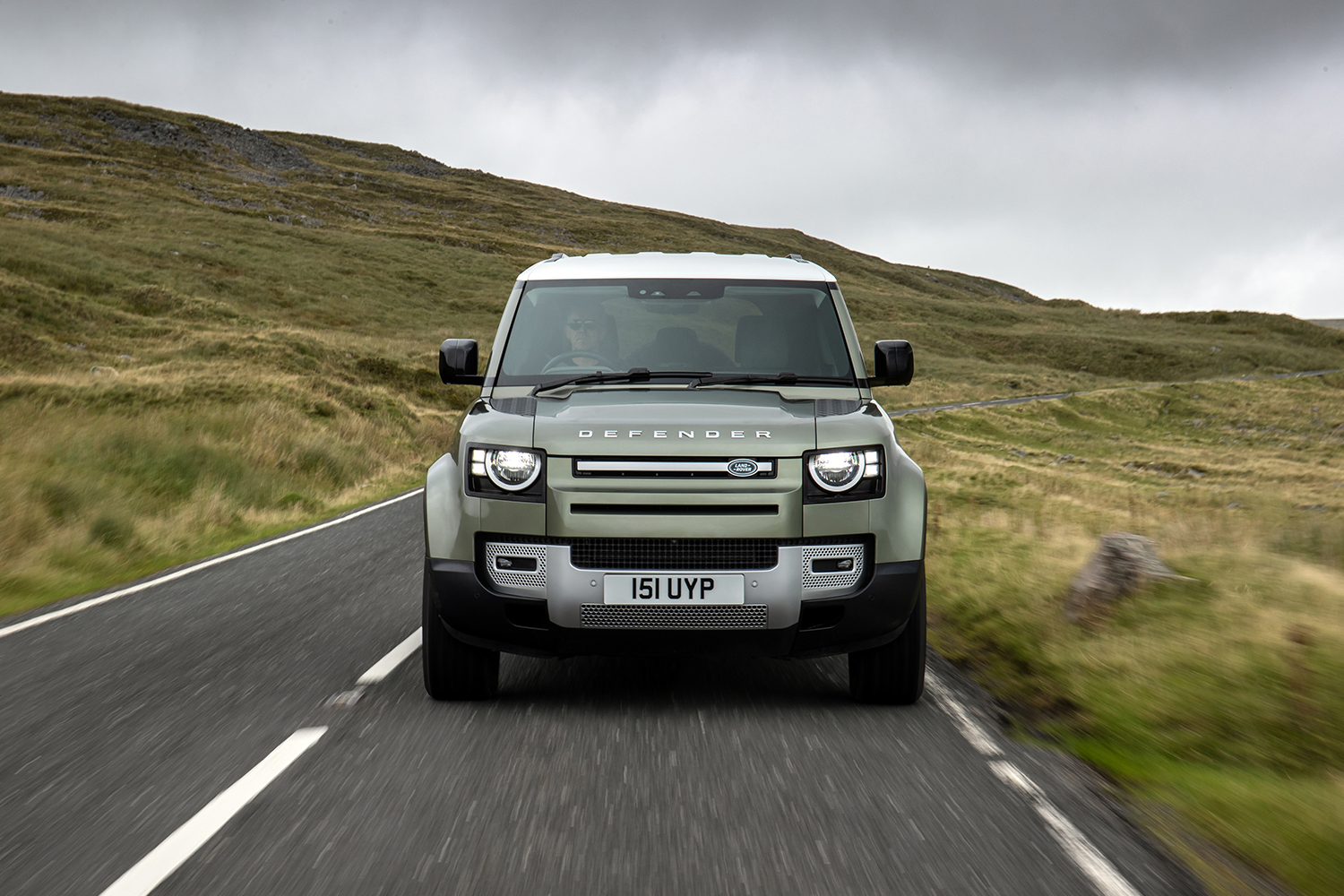 A Land Rover Defender driving down a country road