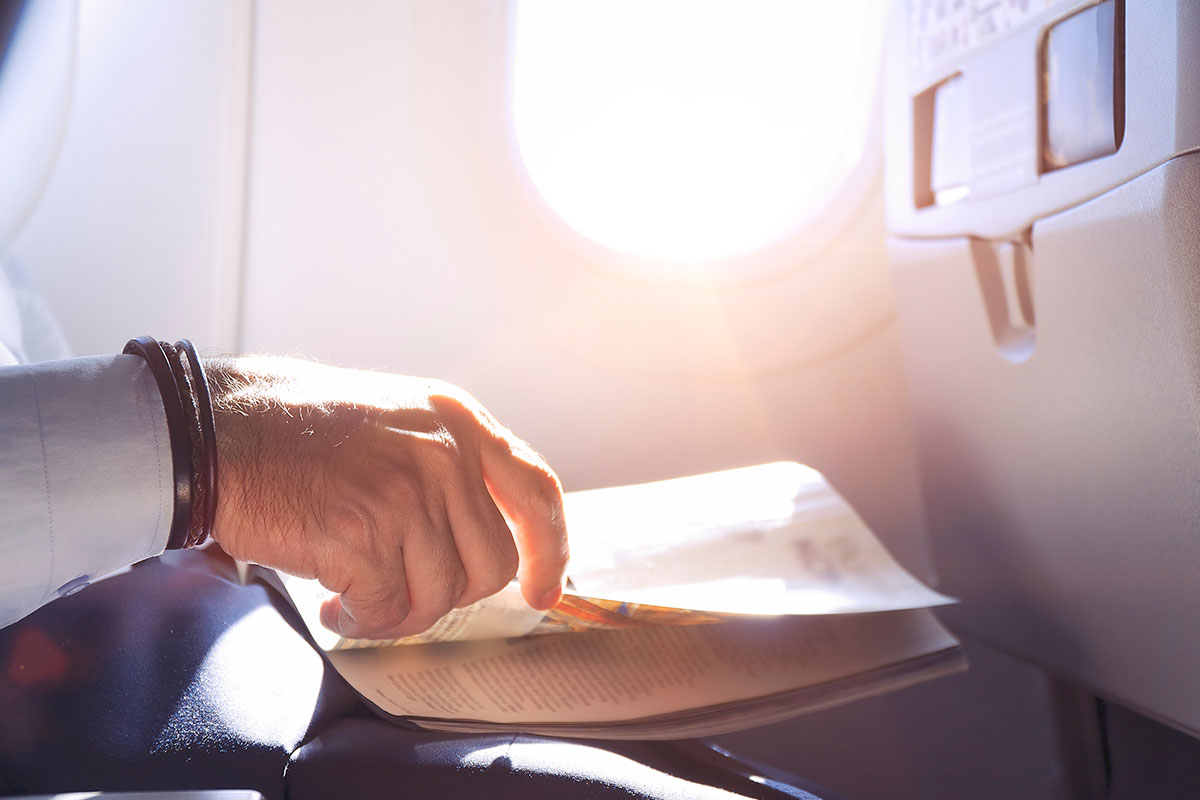 Man reading magazine in airplane - Close up shot of hand