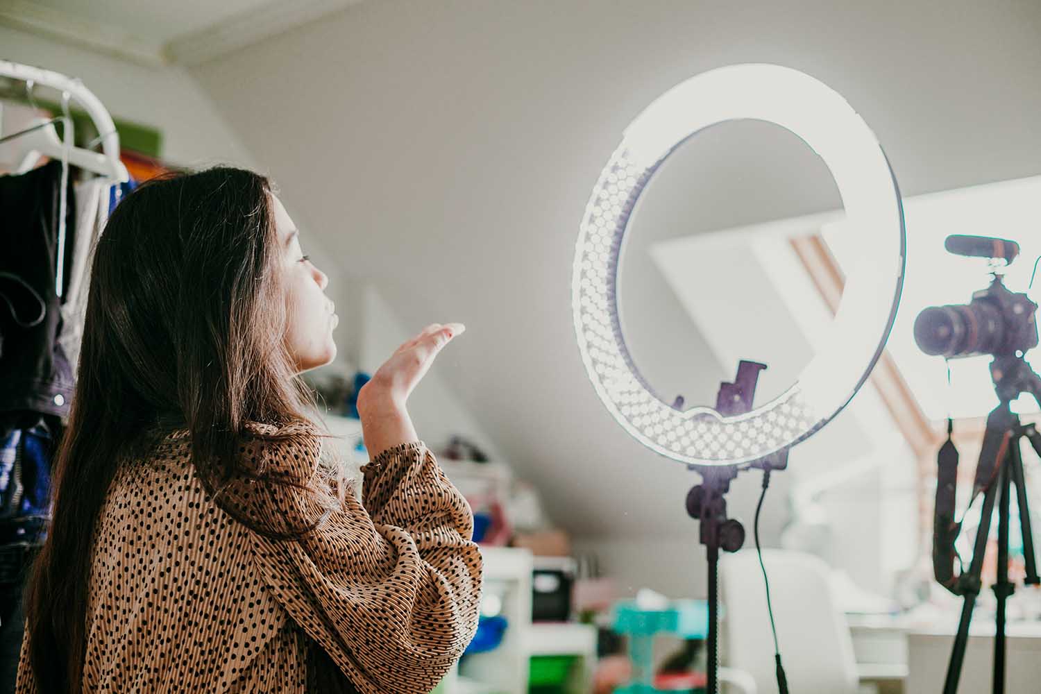 Young female recording video for social media with ring light