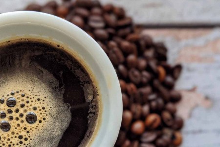 Coffee bean prices are surging around the globe due to three main issues. Pictured here: A cup of coffee and some coffee beans