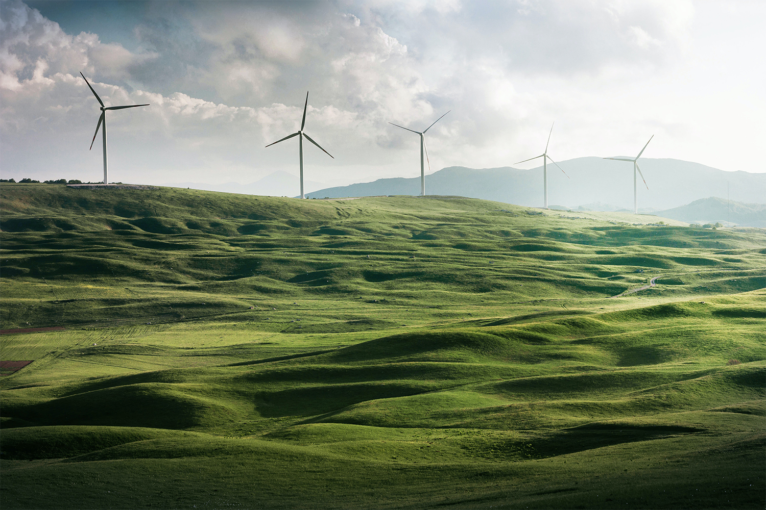 Wind turbines on hills above green fields. What would happen if we switched to green energy and stopped emissions today?