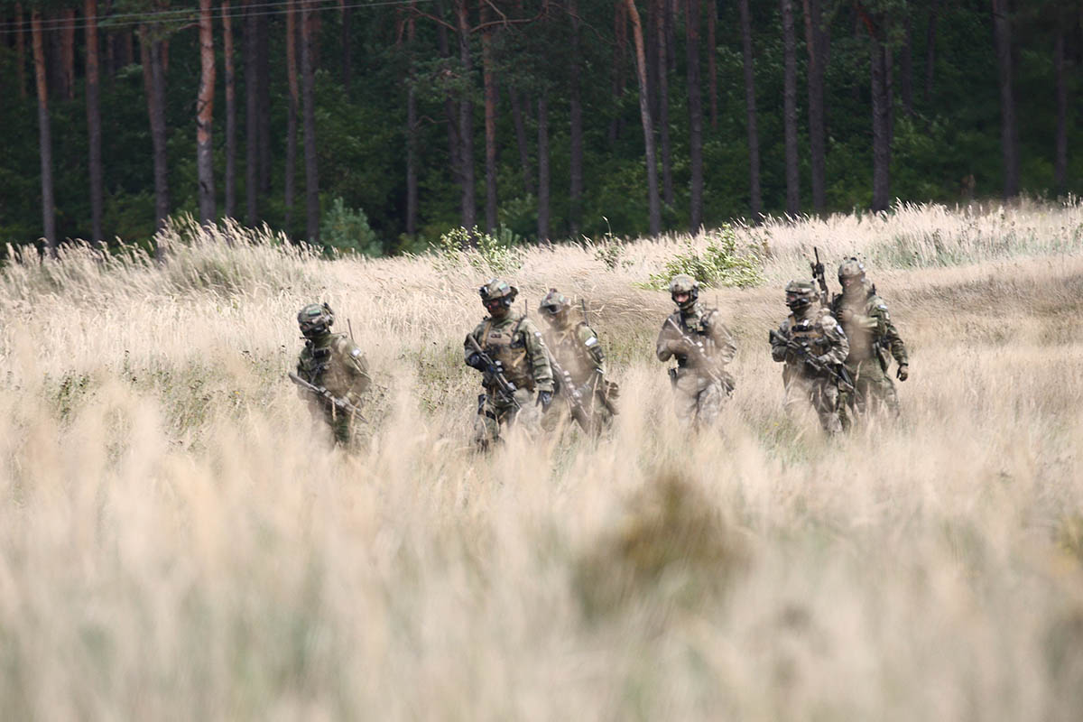 Special forces troops march through a field.