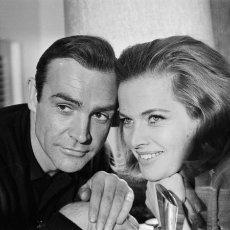 A black and white photo of Sean Connery (James Bond) and Honor Blackman (Pussy Galore) promoting the film "Goldfinger" in 1964