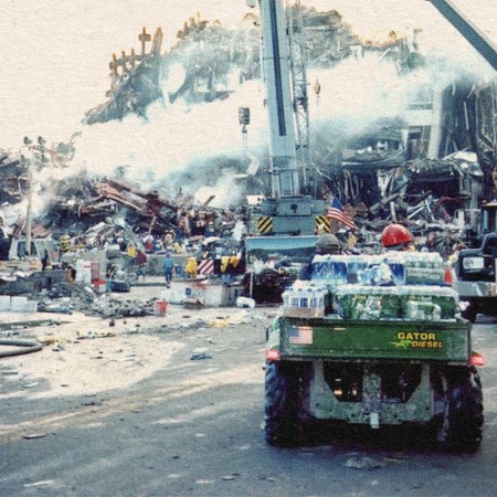 A green John Deere Gator utility vehicle loaded with packs of bottled water facing Ground Zero in the aftermath of the 9/11 terror attacks in New York City, the collapsed towers still on fire and smoking