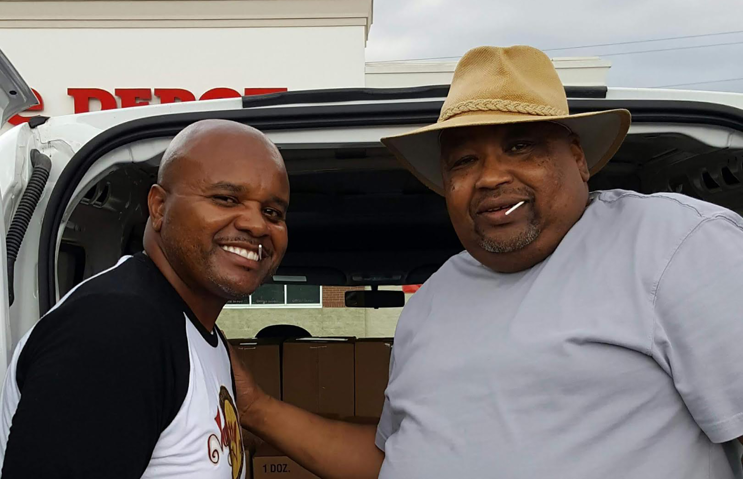 John Perkins of Johnny B's and his father who started the family's successful barbecue joint stand in front of a van.