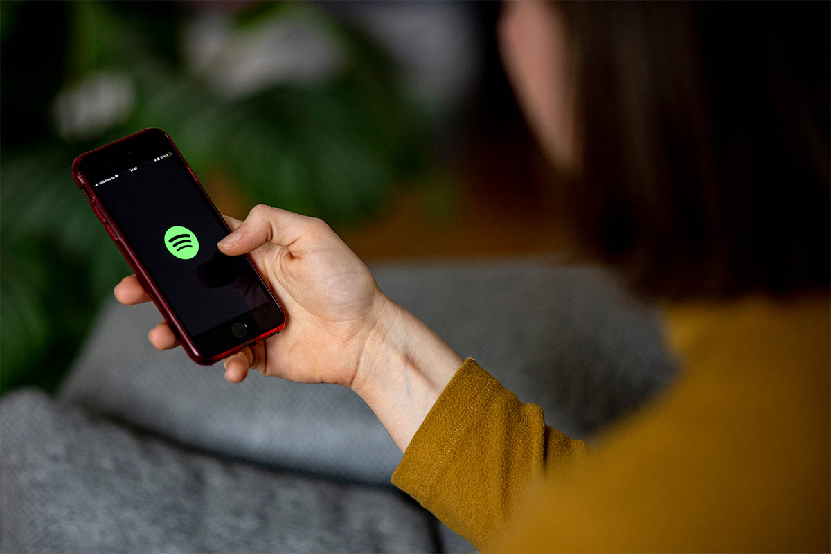 A person using Spotify on a smartphone. The streaming app is draining battery life on iPhones with Apple's latest update.