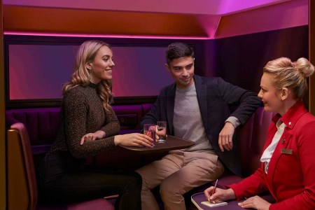 Two passengers on Virgin Atlantic ordering drinks in "The Booth," a new immersive social space on some A350 aircraft