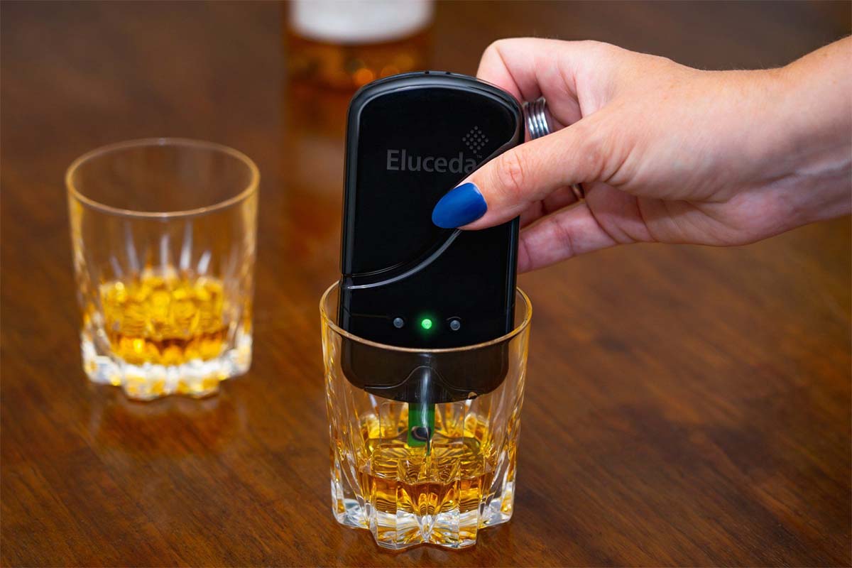 Eluceda's handheld device, the E-Sens, being placed by hand in a glass of whisky. The device reportedly can identify counterfeit whisky.