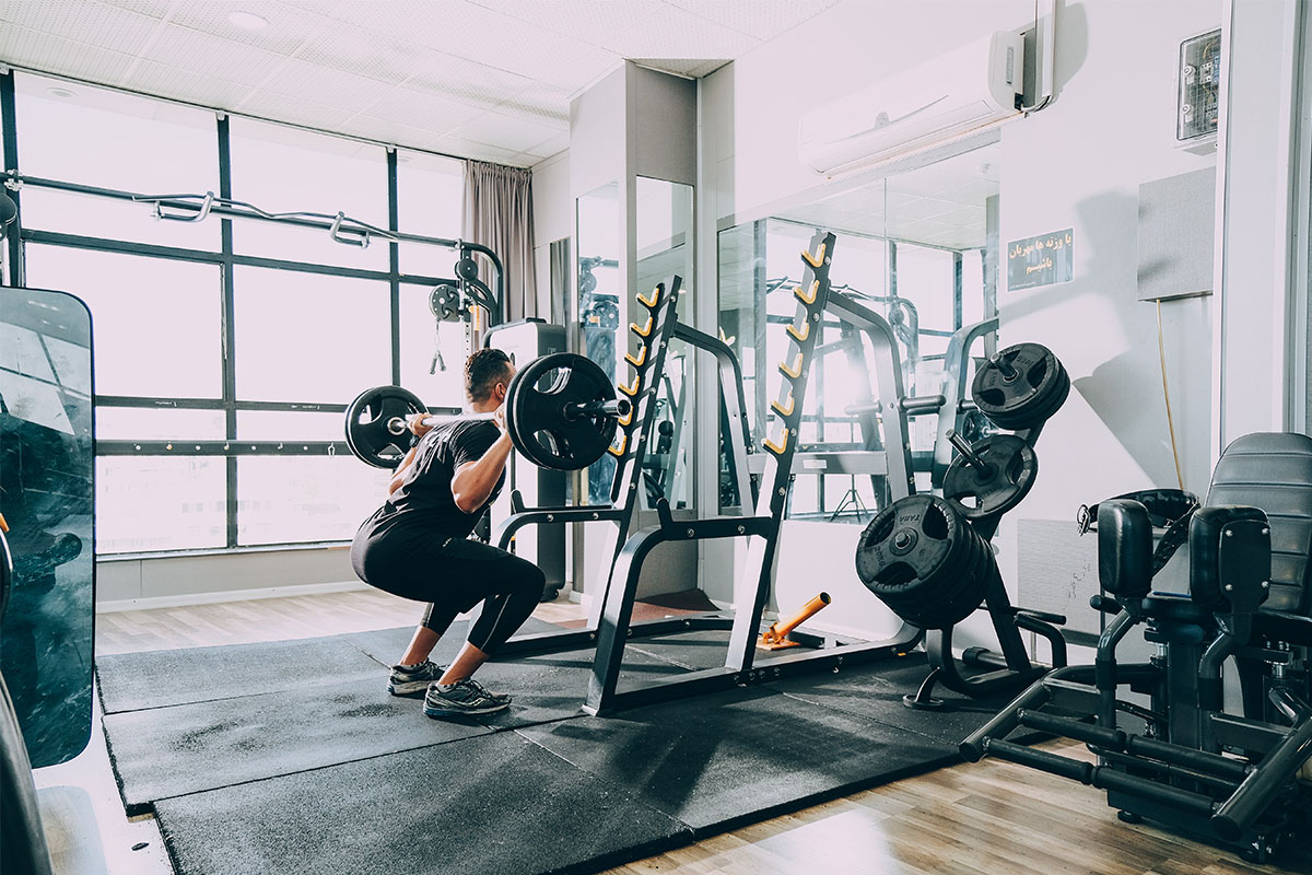 A man performing weighted squats in a gym.