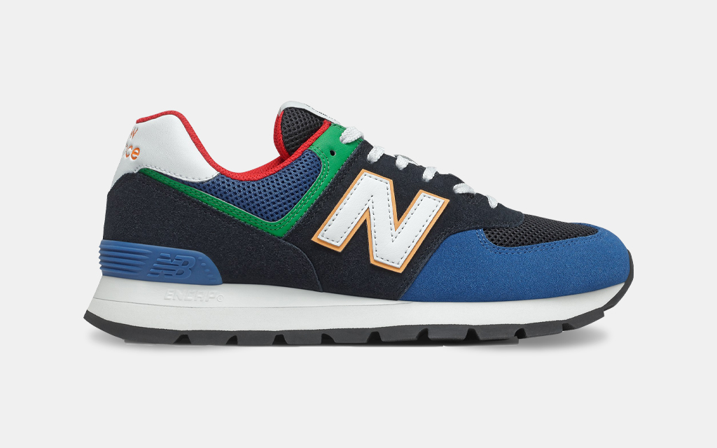 A side shot of the New Balance 574 Rugged Shoe in a black and captain blue colorway. The sneakers are on sale at REI in October 2021.