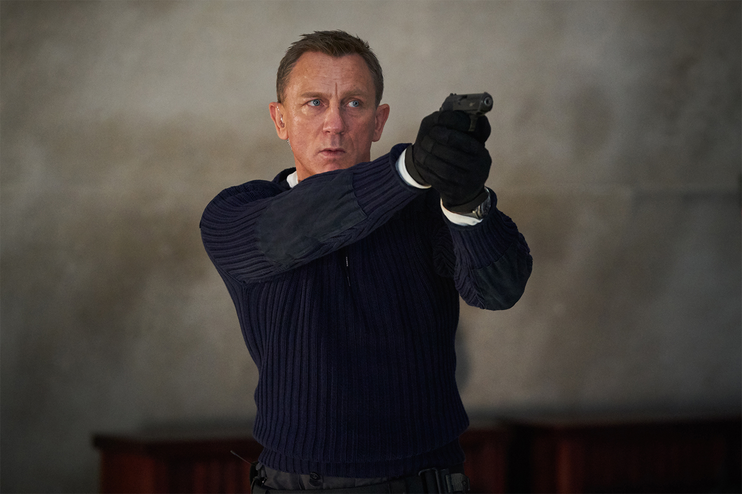 Daniel Craig pointing a gun as James Bond in the latest 007 movie "No Time to Die"