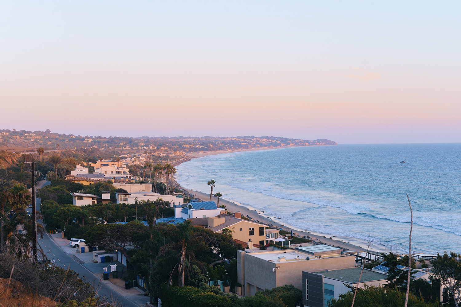 A photo of Malibu, California from above, showing beachfront houses along the ocean