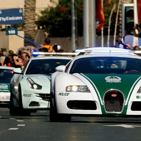 A United Arab Emirates police convoy driving down the street in Dubai featuring a Bugatti, Ferrari and McLaren police car