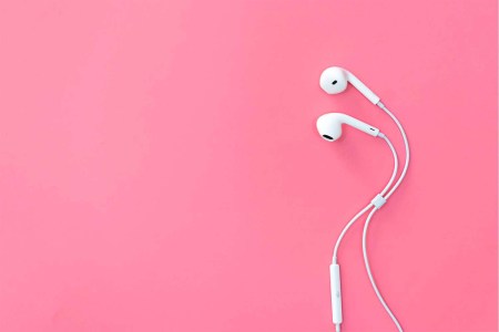 Apple wired headphones on a pink background.