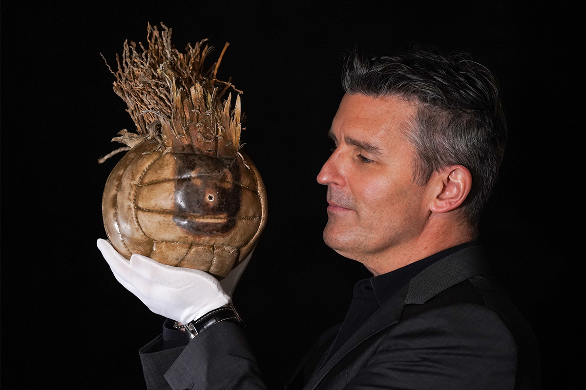 A man holds the "Wilson" volleyball from Cast Away ahead of a prop auction.