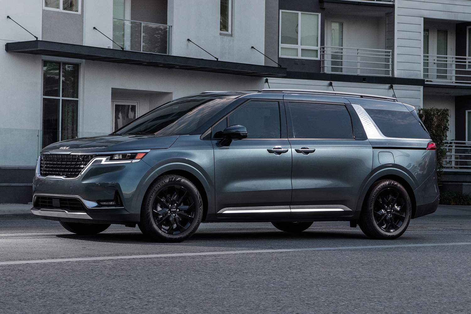 The 2022 Kia Carnival luxury minivan, or MPV, shot from the left side while sitting still on a city street