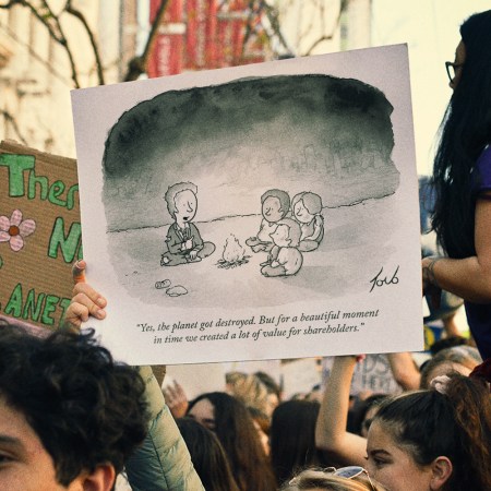 A protester at a climate march holding up a sign with Tom Toro's climate change cartoon from an issue of "The New Yorker" magazine from November 2012