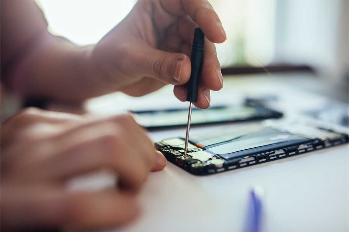 A woman repairing a phone at home. Apple just announced a new program that will allow customers to fix their own phones.