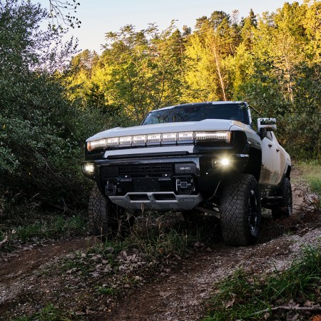 The GMC Hummer EV driving through mud in the woods as part of an engineering test for the electric supertruck