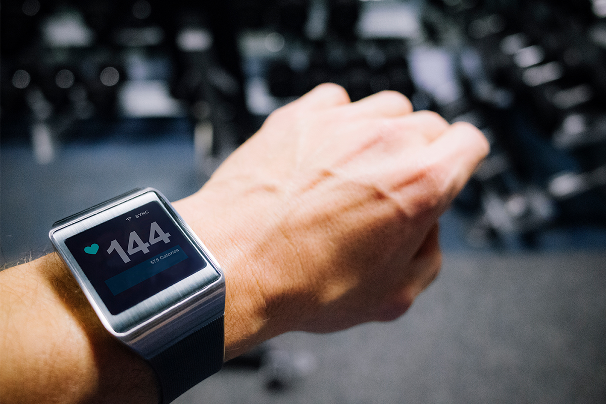 A man wears a fitness tracker in the gym.