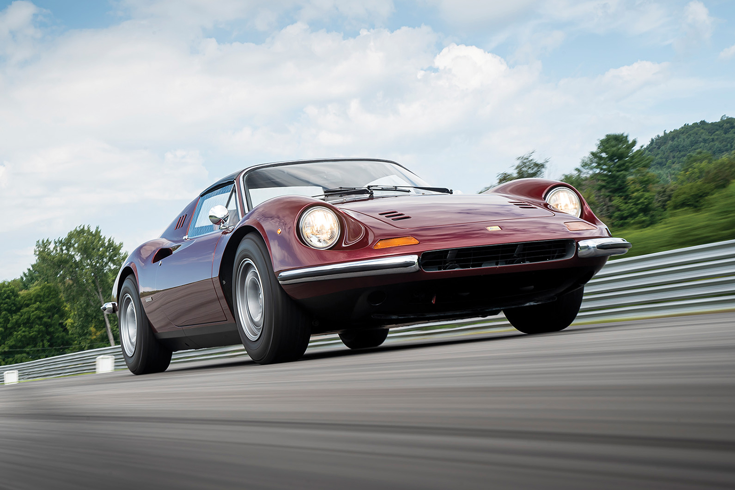 A 1973 Ferrari 246 Dino sports car shot from below as it drives fast down the track. The Italian classic car is on Hagerty's 2022 Bull Market List.