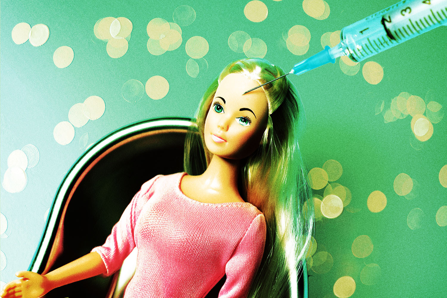 A Barbie doll sits in a chair with a needle near her head, suggesting a Botox injection