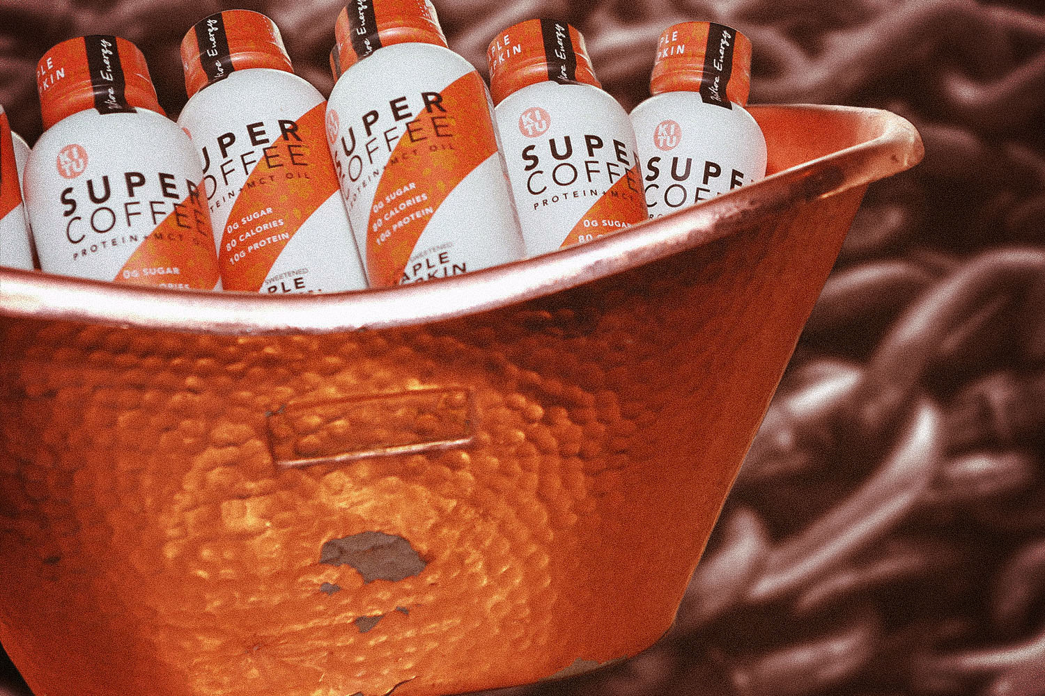 A tub of Super Coffee against a coffee-inspired background.