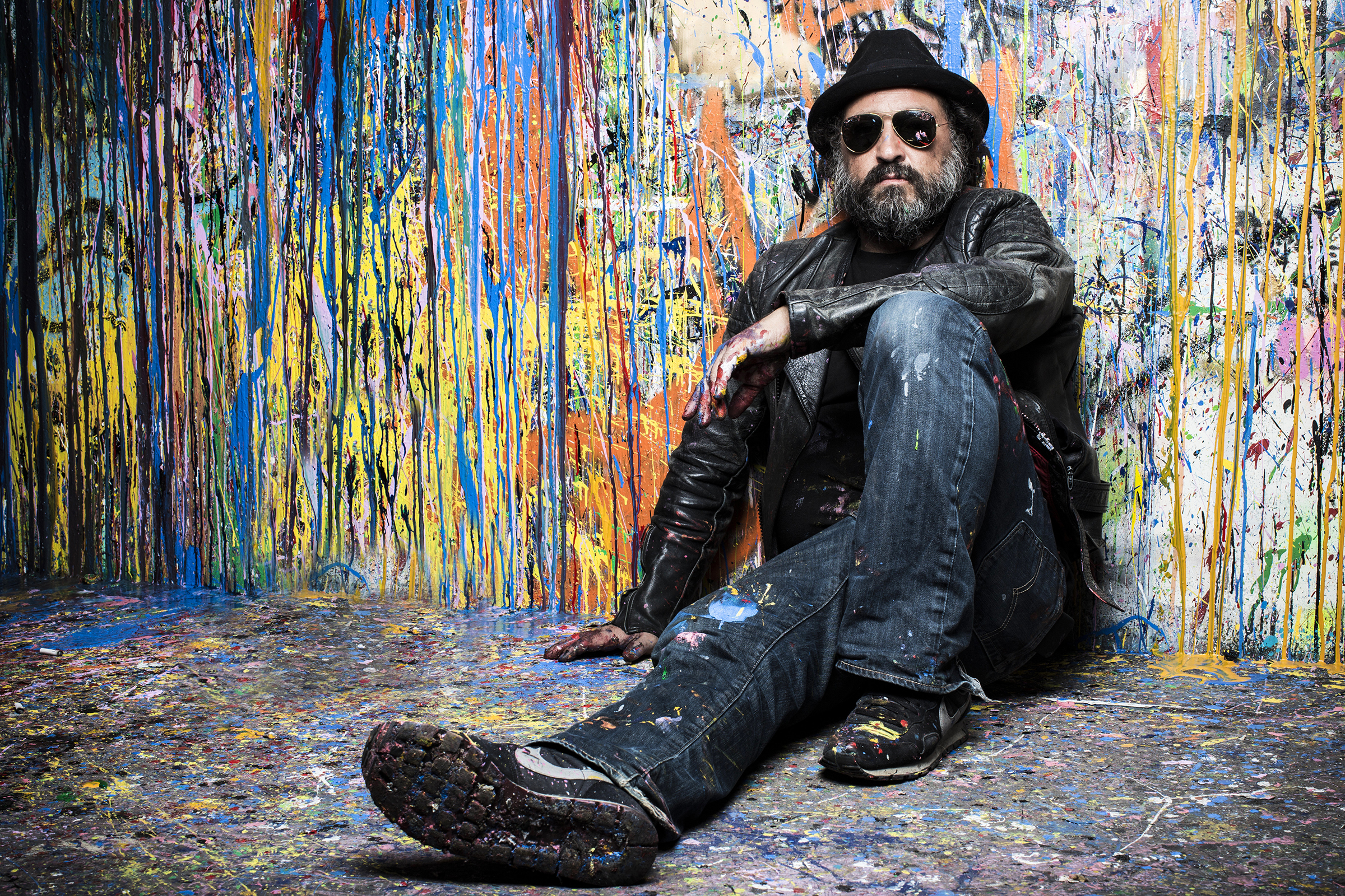 French street artist Mr. Brainwash poses in front of a wall splattered with spray paint