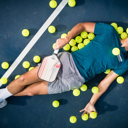 Ben Johns, the no. 1-ranked men's pickleball player in the world, lies on a pickleball court, surrounded by pickleballs