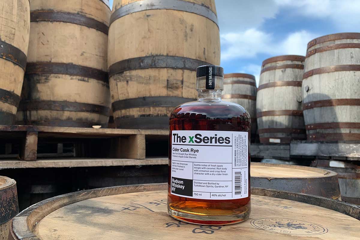 A bottle of Cider Cask Rye from Hudson Whiskey on top of barrels. The release is part of a new trend for whiskey brands to release ryes that have undergone secondary maturations