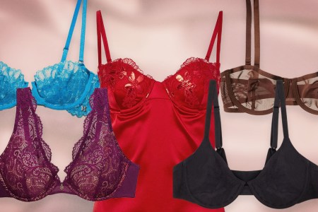 A blue bra, purple bra, brown bra and black bra surrounding a red silk slip dress, perfect Valentine's Day gifts, on a pink background.