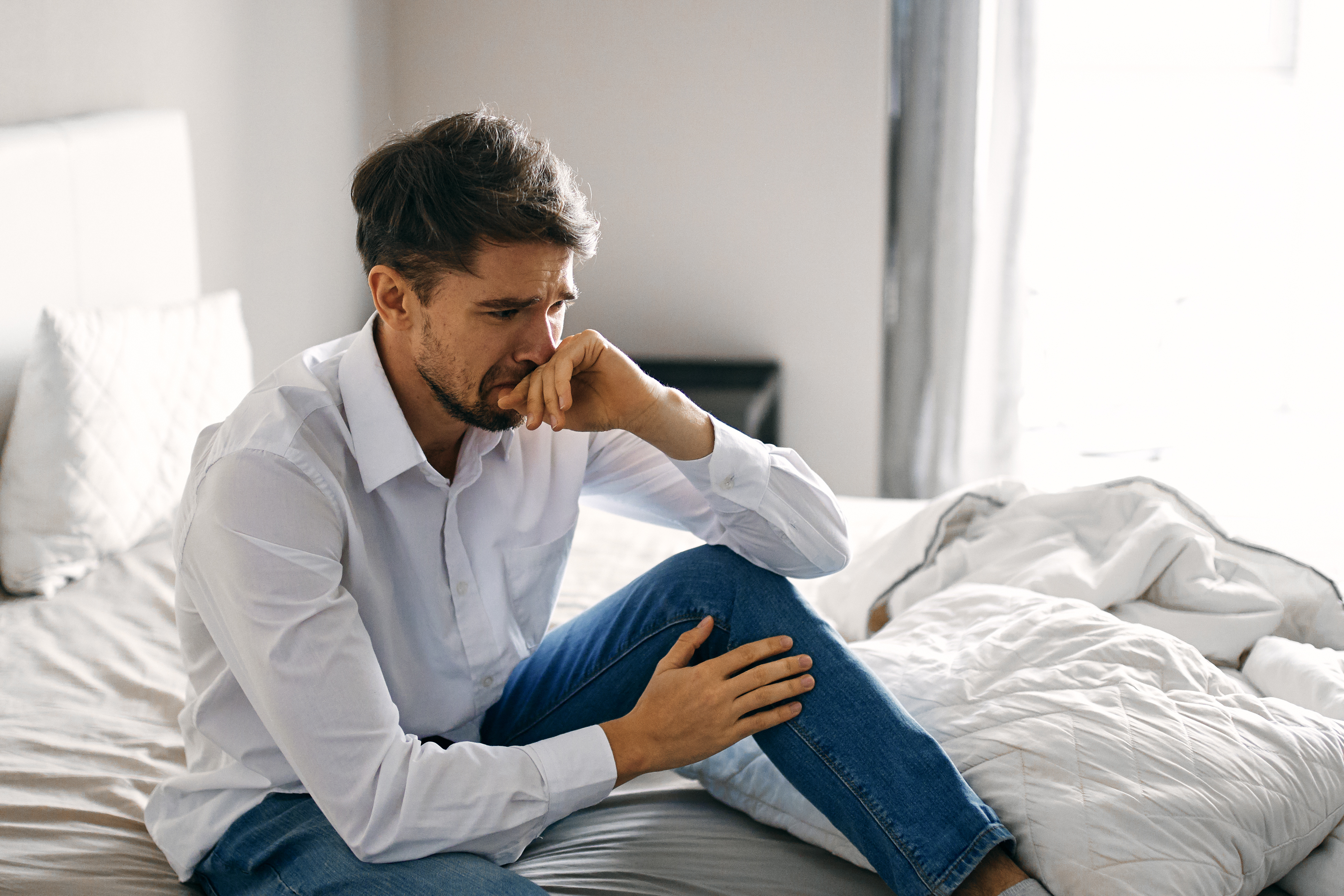 A man sits on a bed and cries