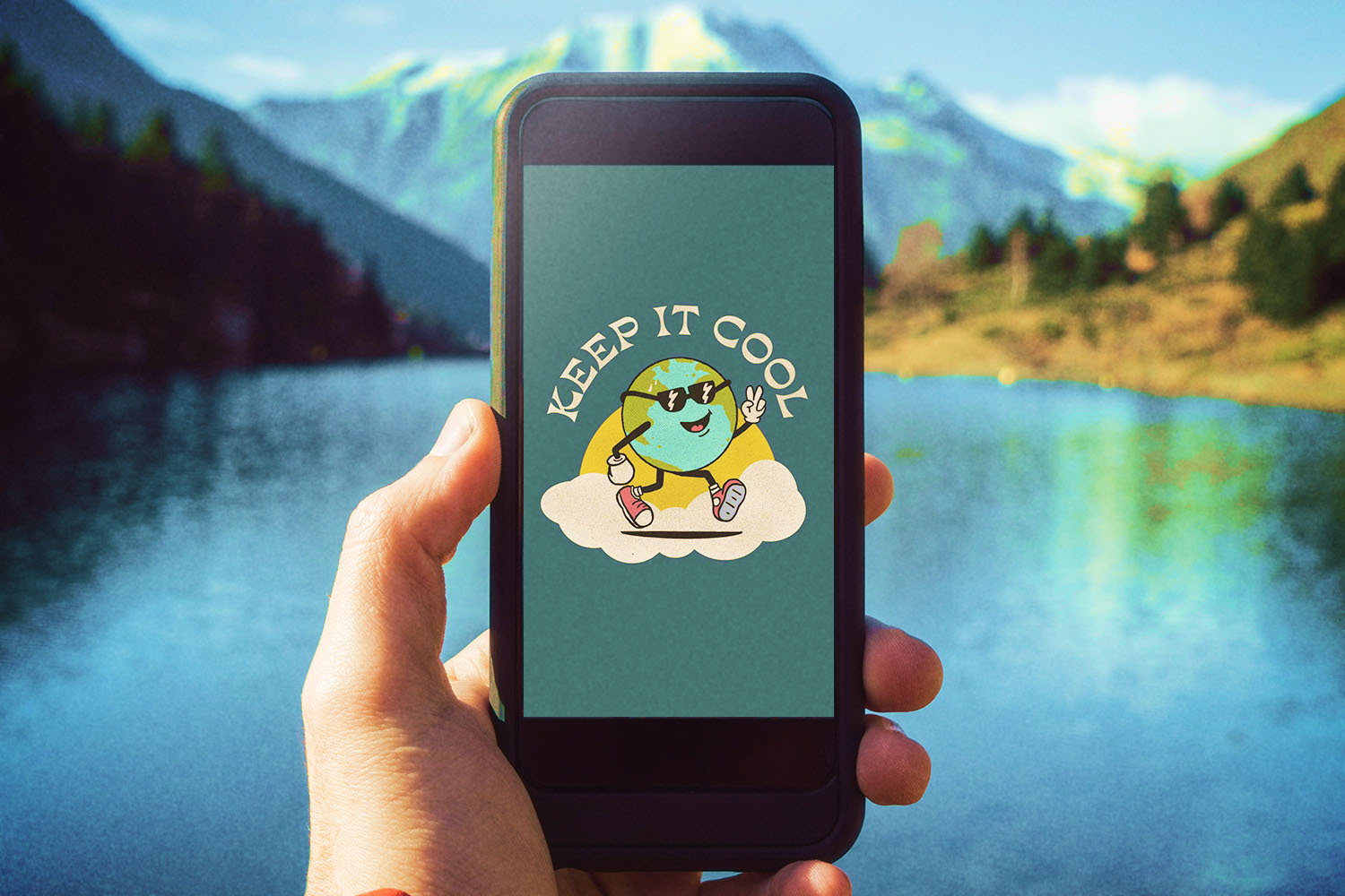 A person holding a smartphone up with a lake and mountain in the background. On the phone is United By Blue's NFT of Eddy Earth, the sustainable brand's new mascot.