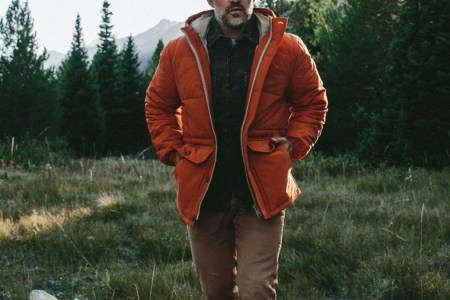 a model walking outdoors with the Taylor Stitch Whitney Parka and Camp Pants on