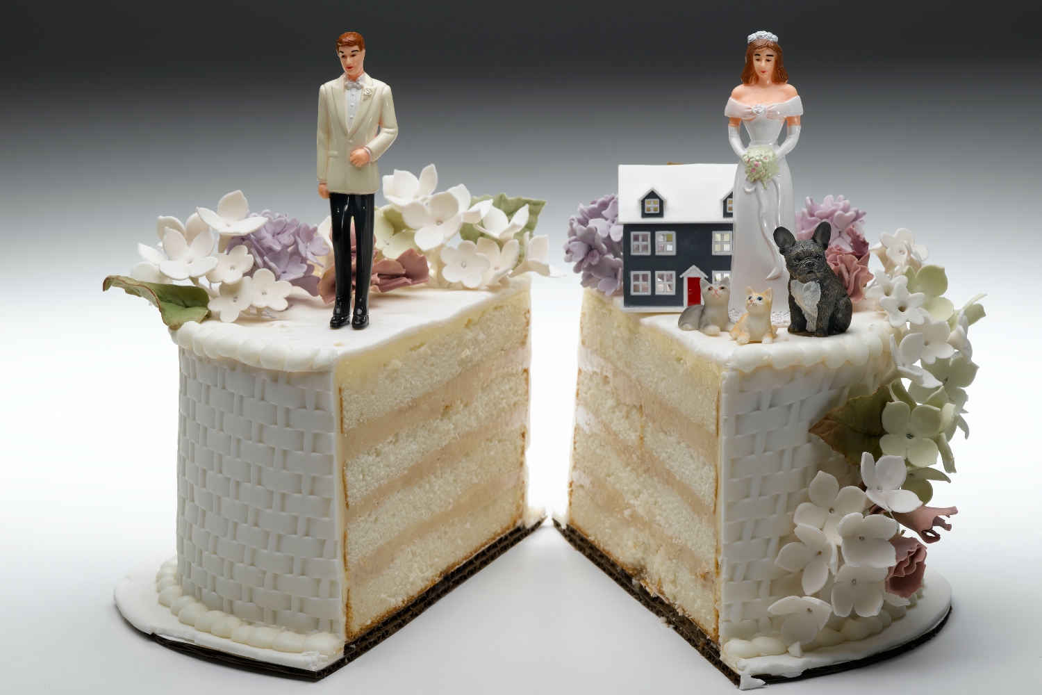 Bride and groom figurines standing on two separated slices of wedding cake