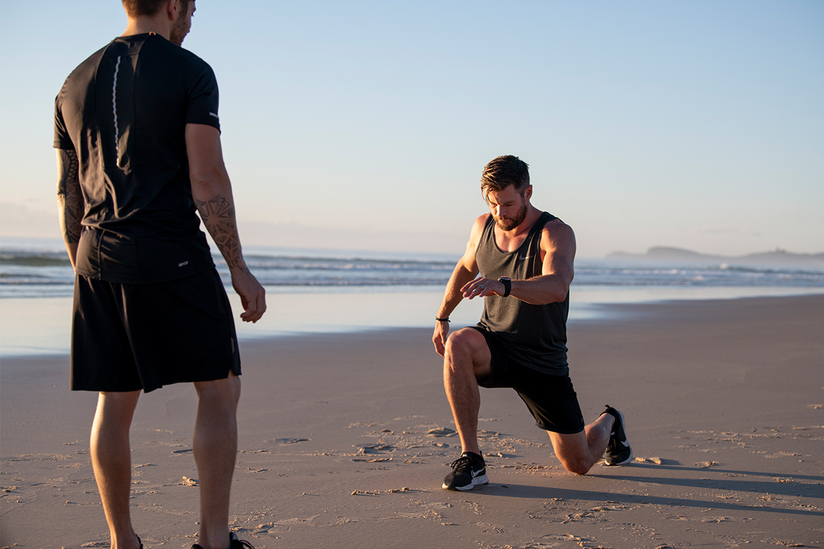 Chris Hemsworth lunging on a beach.