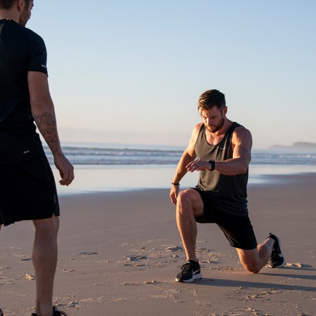 Chris Hemsworth lunging on a beach.