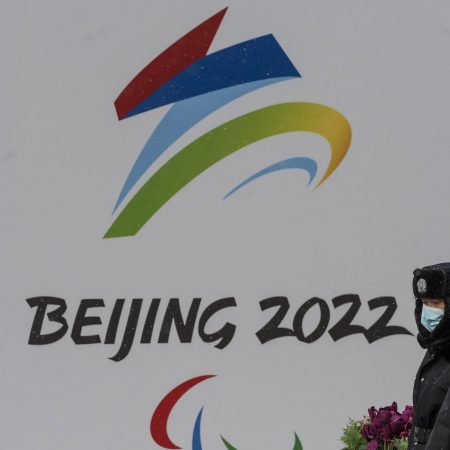 Security officers walk by a billboard for the Beijing 2022 Winter Olympics