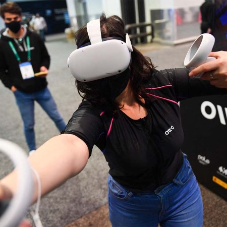 An attendee demonstrates the Owo vest, which allows users to feel physical sensations during metaverse experiences such as virtual reality games, including wind, gunfire or punching, at the Consumer Electronics Show (CES) on January 5, 2022 in Las Vegas, Nevada. - The CES tech show threw open its doors Wednesday in Las Vegas despite surging Covid-19 cases in the United States, as one of the world's largest trade fairs tried to get back to business. Despite some obvious gaps on the showfloor -- after high-profile companies like Amazon and Google cancelled over climbing virus risk -- crowds of badge-wearing tech entrepreneurs, reporters and aficionados poured through venues.